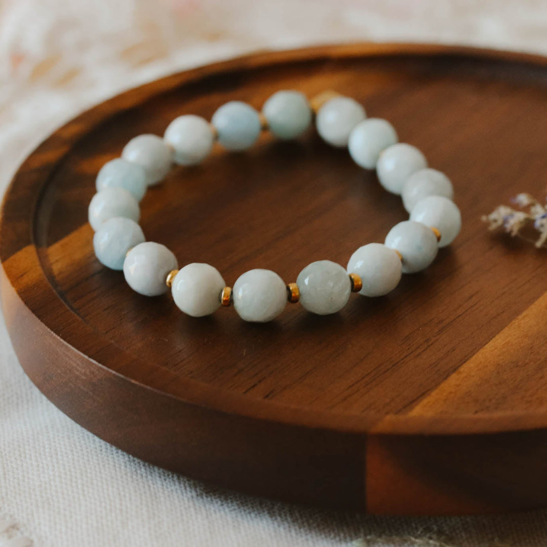 Aquamarine beaded bracelet on a wooden tray with a soft background