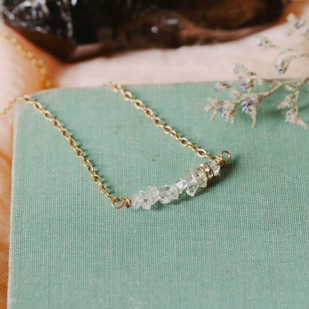 Gold necklace with small diamonds on a green surface with a blurred background