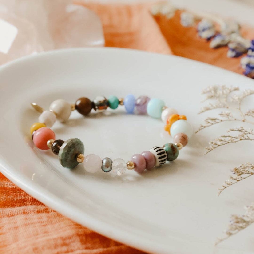 Colorful beaded bracelet on a white dish with an orange fabric background