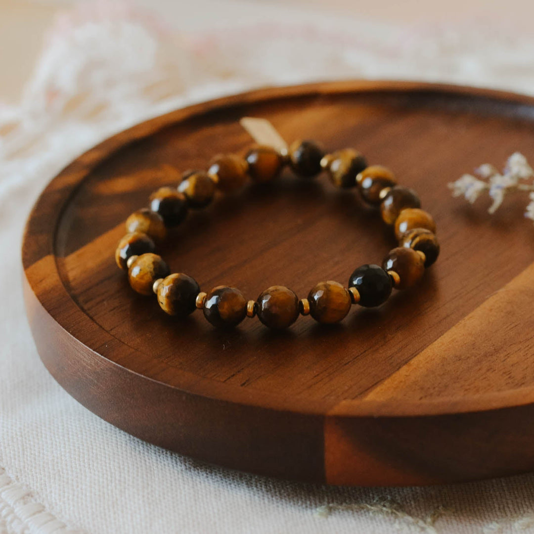 Bracelet on a wooden tray with a delicate white flower