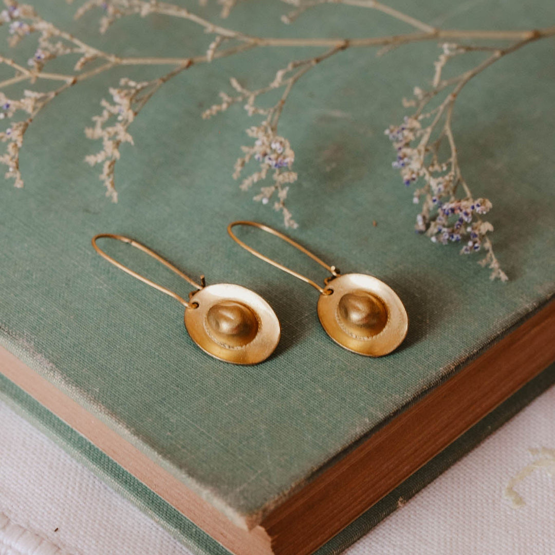 Gold earrings on an old book with dried flowers