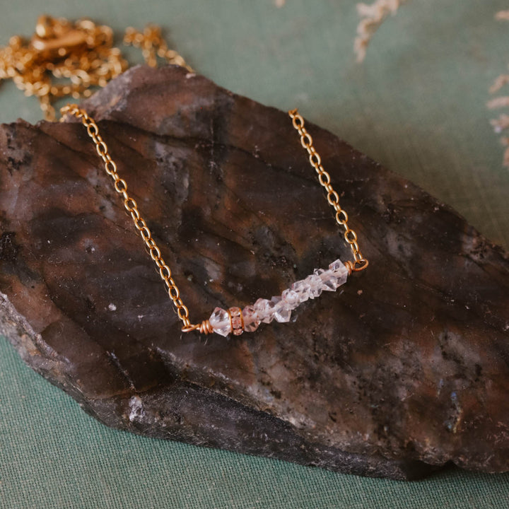 Gold necklace with clear stones on a dark stone surface